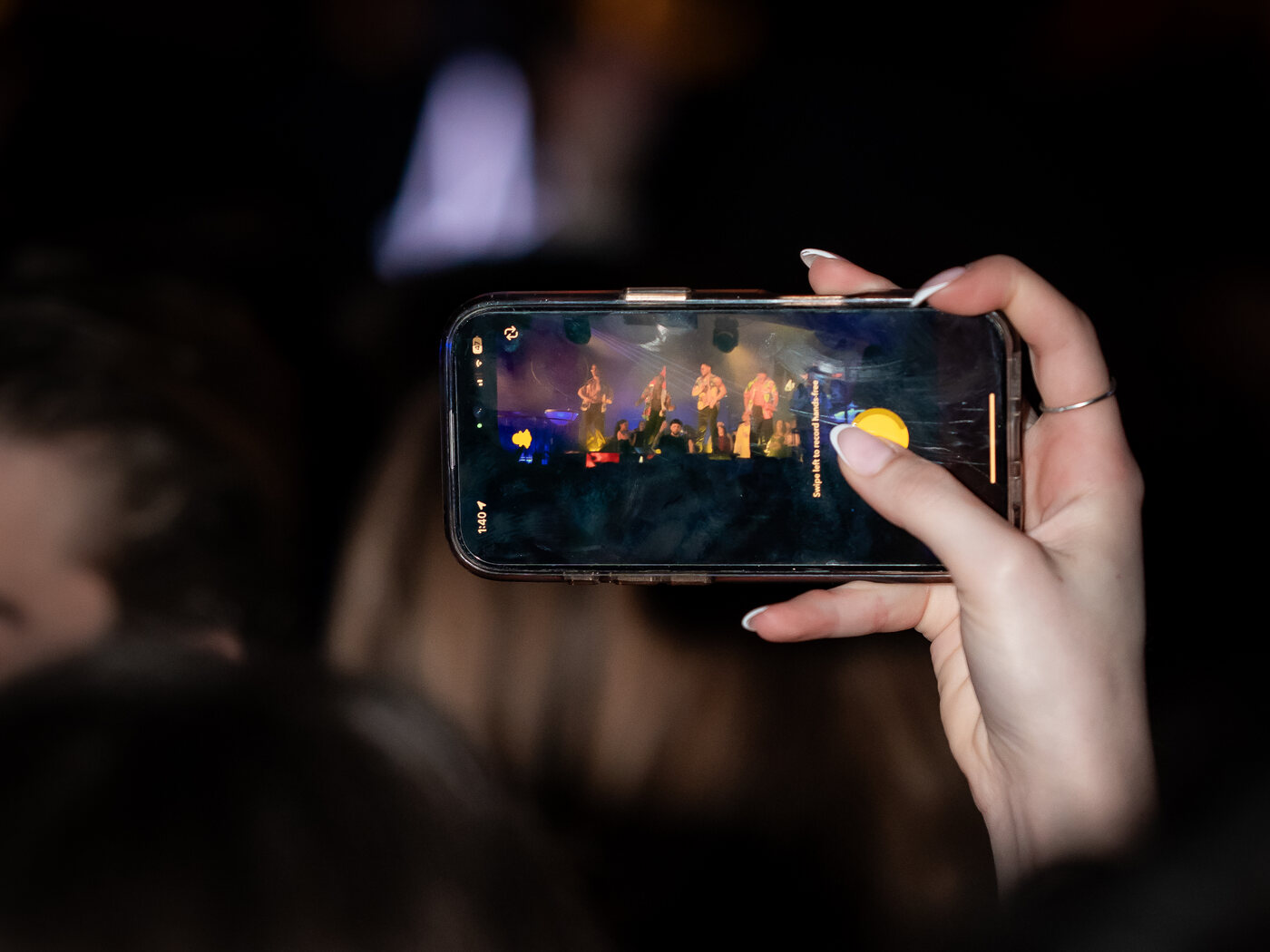 Una ragazza riprende col telefono lo spettacolo sul palco dell'Art Cafè